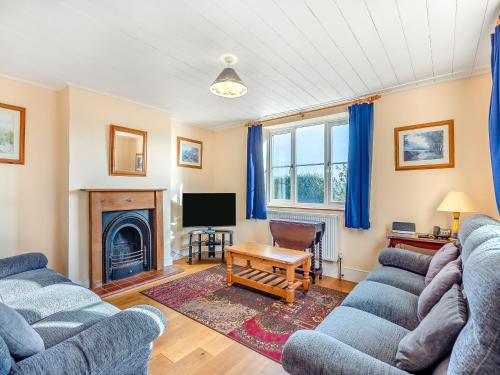 a living room with two blue couches and a tv at Prosperous Villa in Puncknowle
