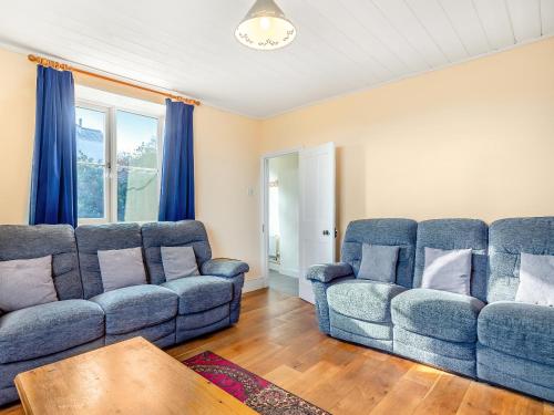 a living room with two blue couches and a table at Prosperous Villa in Puncknowle