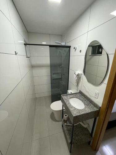 a bathroom with a toilet and a sink and a mirror at AL&V Hotel in Santa Tereza do Oeste