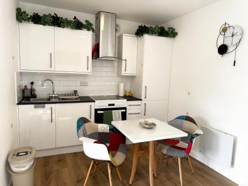 a kitchen with white cabinets and a table and chairs at Garden Studio in Bristol