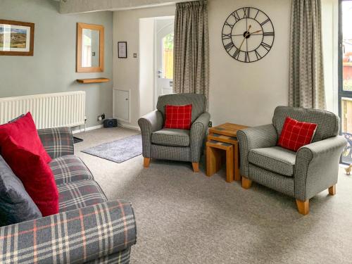 a living room with two chairs and a clock on the wall at The Chapel in Staveley