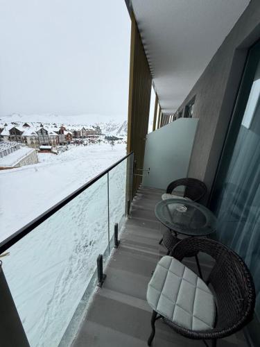 a balcony with two chairs and a table and snow at New Gudauri Atrium in Gudauri