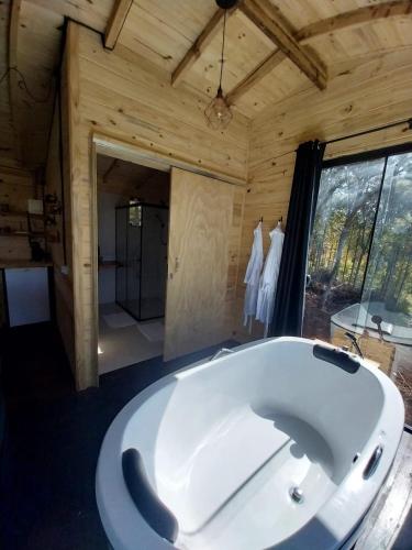 a large white tub in a room with a large window at Cabanas do Arvoredo in São José do Cerrito