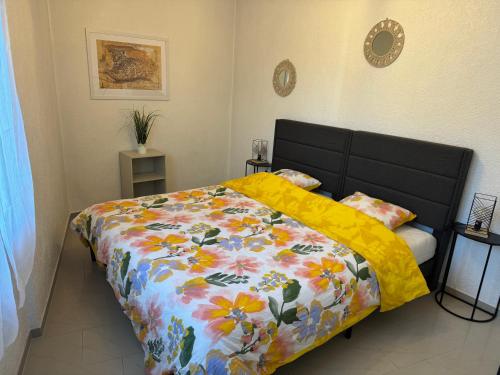 ein Schlafzimmer mit einem Bett mit geblümter Bettdecke in der Unterkunft EJolie in Illzach