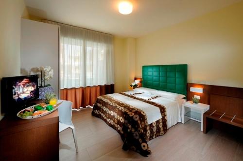 a bedroom with a large bed and a television at Hotel Luciana in Bibione