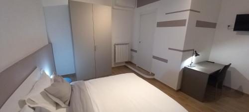 a bedroom with a white bed and a desk with a lamp at Il Palazzetto in Velletri