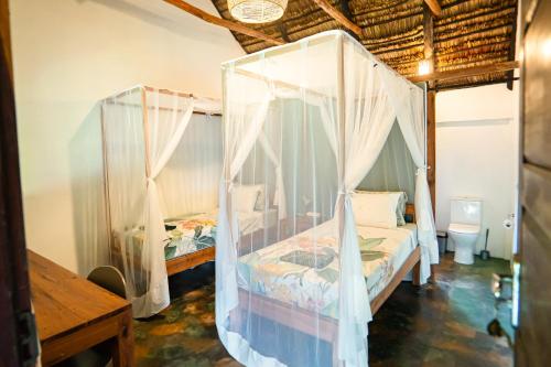 a bedroom with two beds with mosquito nets at Kitesurf Tofo House - 1 minute walk from beach and center in Praia do Tofo