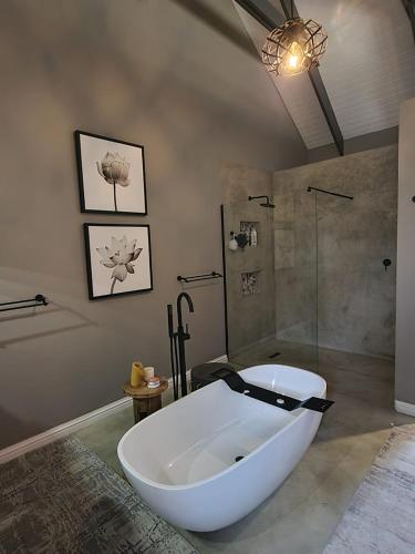 ein Badezimmer mit einer großen weißen Badewanne und einer Dusche in der Unterkunft Blomberg in Clanwilliam