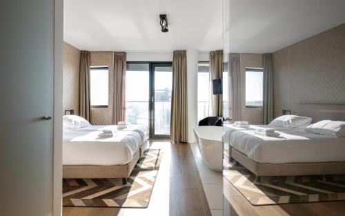 a hotel room with three beds and a bath tub at Maris Apartments in Egmond aan Zee