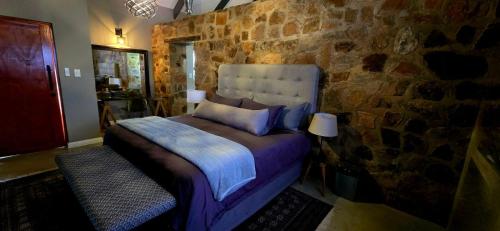 ein Schlafzimmer mit einem Bett vor einer Steinwand in der Unterkunft Blomberg in Clanwilliam