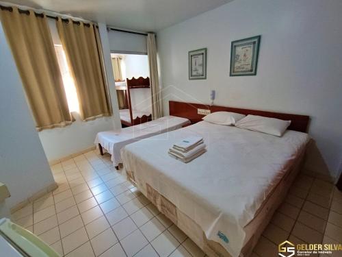 a hotel room with two beds and a window at Flats CTC Araras in Caldas Novas