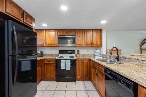 a kitchen with wooden cabinets and a black refrigerator at Pier Point South Ocean View Condo B-22 in St. Augustine