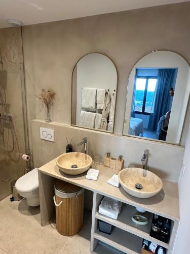 two sinks in a bathroom with a toilet and mirrors at Prestige villa Estrella in Fayence