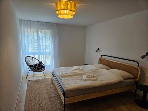 a bedroom with a bed and a chair and a window at Summit View Apartment in Spiez