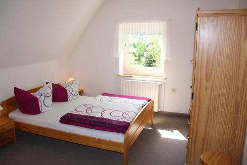 a bedroom with a bed with purple sheets and a window at Pension Haus Pentacon in Kurort Altenberg