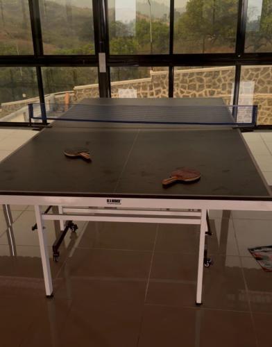 a ping pong table with two shoes on top of it at The Sixth Abode Farms 5 BHK Villa with Swimming Pool, Turf, Lawn & Indoor Games- Khopoli in Jambhulpāda