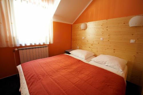 1 dormitorio con 1 cama grande de color naranja y ventana en Terme Zreče – Vile Terme Zreče, en Zreče