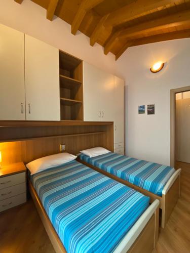 two beds in a room with white cabinets and wooden floors at Casa Sole in Vercana