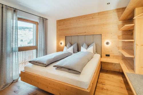 a bedroom with a large bed with a wooden wall at Kuenzerhof Apartments in Braies