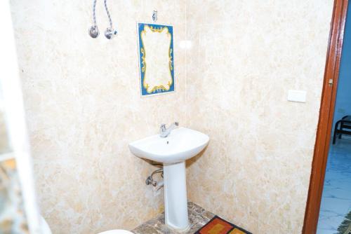 a bathroom with a sink and a picture on the wall at Aisha Guest House And Restaurant in Al Aqālitah