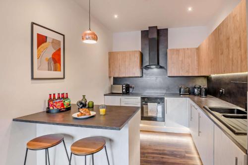 a kitchen with white cabinets and a counter with stools at Modern Bright 3 Bedroom Apartment In Converted Brewery With Secure Undercover Gated Parking in Hull