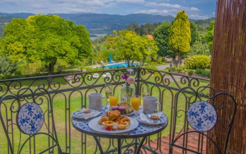a table with a plate of food on a balcony at Solar Alegria Lodge in Oliveira de Frades