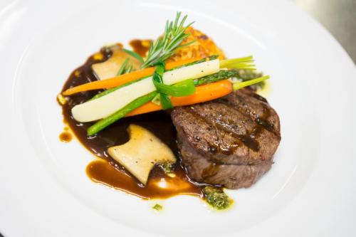a white plate with a steak with carrots and gravy at Hermanns Hotel Zum Goldenen Stern in Jüterbog