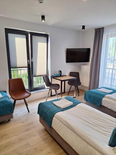a hotel room with two beds and a table and chairs at VILLA 17 Noclegi in Płock