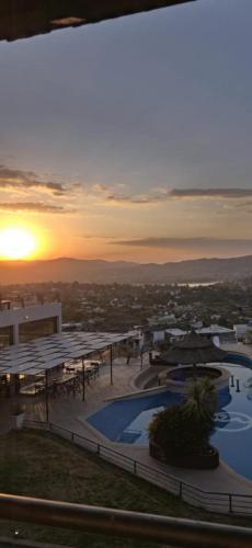 a view of a resort with two pools and a sunset at ERNESTINA VILLAGE Resort Apart & suites in Villa Carlos Paz