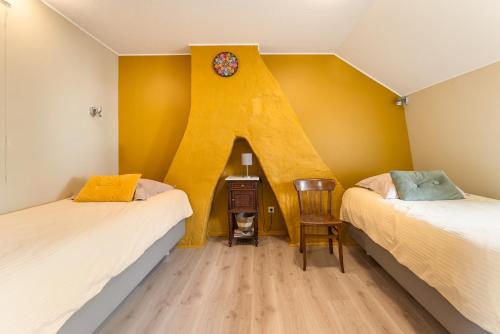 a room with two beds and a clock on the wall at Het Rustplekje in Alveringem