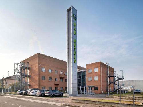 a building with a sign in front of a parking lot at B&B HOTEL Milano Cologno Studios in Cologno Monzese