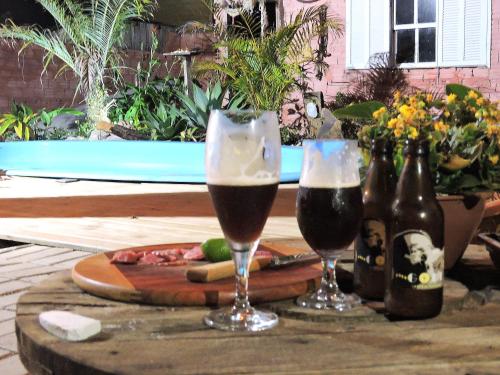 dos vasos de cerveza y botellas en una mesa en Pousada Villa da Nascente, en Florianópolis