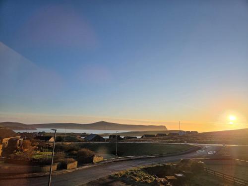 a sunset over a city with a road and a body of water at Sandyloch Flat in Lerwick