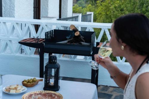 a woman drinking a glass of wine in front of a grill at El Rincón de Muñoz - La Alpujarra in Yegen