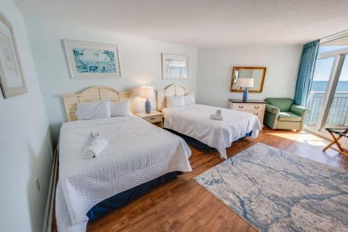 a bedroom with two beds and a chair and a window at Baywatch Renovated, Unobstructed Oceanfront Views in Myrtle Beach