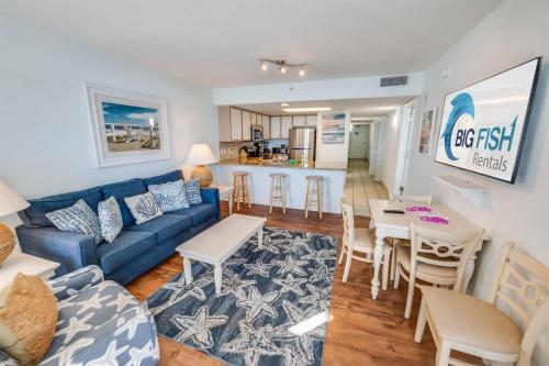 a living room with a blue couch and a kitchen at Baywatch Renovated, Unobstructed Oceanfront Views in Myrtle Beach
