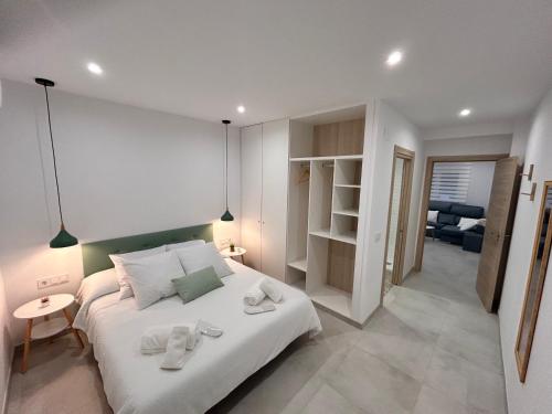 a bedroom with a white bed with towels on it at One Apartamentos in Torreorgaz