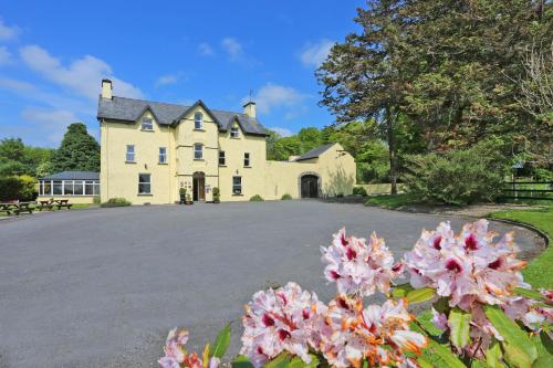 a large house with pink flowers in front of it at Carrygerry Country House in Shannon