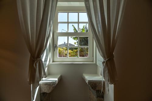 a window with curtains and a bench in front of it at Boutique Hotel Casa da Brêa Viana do Castelo in Viana do Castelo
