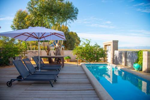 a deck with chairs and an umbrella next to a swimming pool at Marrian George Hotel in Koringberg
