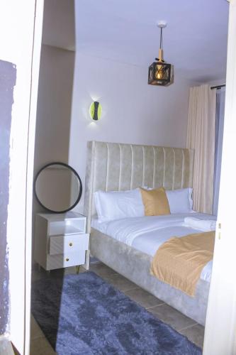 a bedroom with a bed with a mirror and a table at TanuStays - Modern 1 Bedroom at Royal Suburbs Tsavo, near TRM in Nairobi