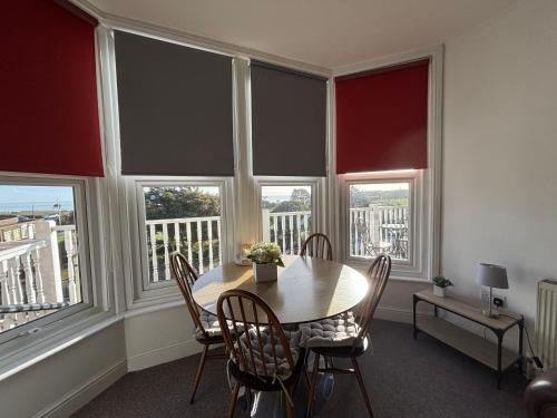 a dining room with a table and chairs and windows at Seabreeze Apartment in Eastbourne