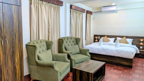 a hotel room with two chairs and a bed at Tuyu Chhye in Kathmandu