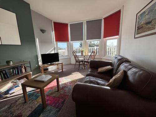 a living room with a leather couch and a table at Seabreeze Apartment in Eastbourne