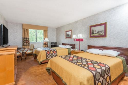 a hotel room with two beds and a flat screen tv at Super 8 by Wyndham Hancock MD in Hancock