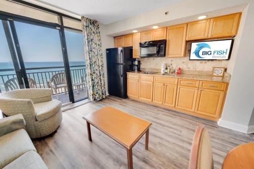 a living room with a couch and a table and a kitchen at New Beachfront, Condo Simply Amazing Pools & Views in Myrtle Beach