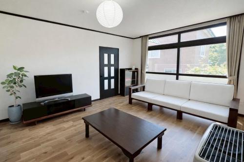 a living room with a white couch and a tv at 椴松 l フルリフォーム l 貸切の一軒家 l 千歳空港まで30分 l Todomatsu in Yuni