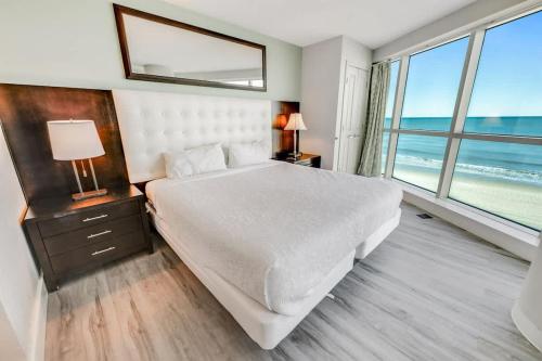 a bedroom with a large bed with a view of the ocean at New Corner Suite 2BR, Direct Ocean and City Views in Myrtle Beach