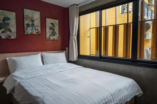 a bedroom with a large bed with a window at Wat We See Bangkok Hostel in Bangkok