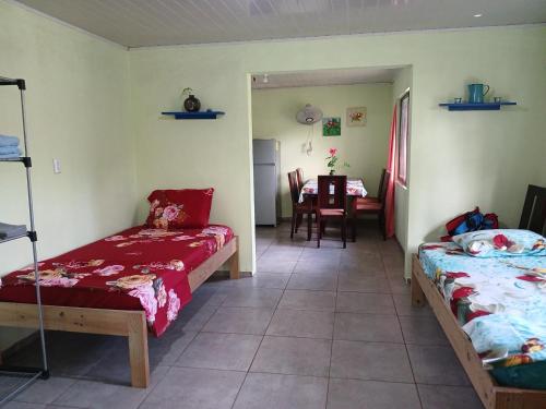 a room with two beds and a dining room with a table at Casa Shakira in Puerto Jiménez